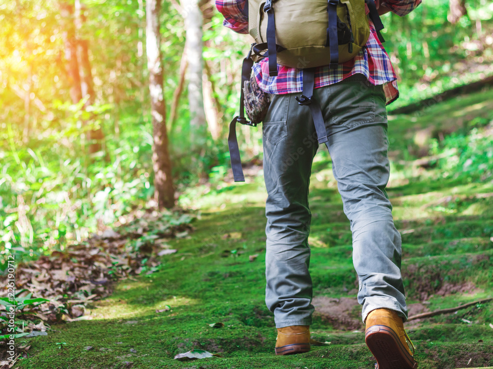 Hiking man with backpack and trekking boots on the bright green moss passage trail in forest Hiking man with backpack and trekking boots on the bright green moss passage trail in forest