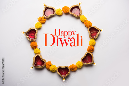 Happy Diwali Greeting Card made using sweets, or fire crackers or Diya or flowers, selective focus photo