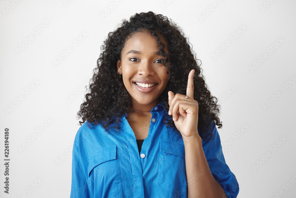 I have an idea. Cheerful cute African student girl with voluminous hair smiling excitedly and raising fore finger, full of great ideas while working on her home assignment, thinking outside the box I have an idea. Cheerful cute African student girl with voluminous hair smiling excitedly and raising fore finger, full of great ideas while working on her home assignment, thinking outside the box