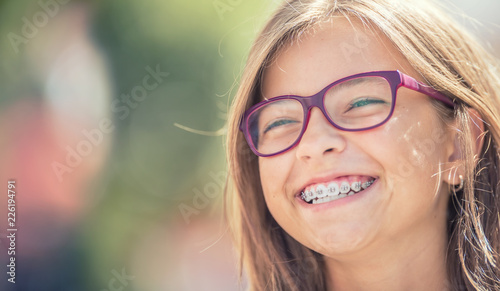 Fototapeta Naklejka Na Ścianę i Meble -  Portrait of a happy smiling teenage girl with dental braces and glasses