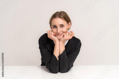 Portrait of a beautiful brunette girl on a white background at the table with different emotions.