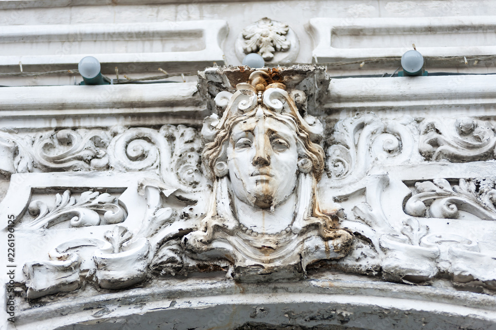 Фрагмент фасада здания, гипсовая маска женской головы античного персонажа. Декор в плачевном состоянии как и весь фасад здания