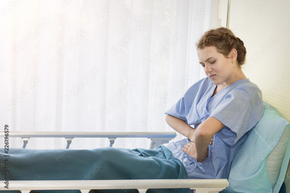 Fototapeta premium Beautiful young woman patient with period pain on hospital bed room.Copy space.