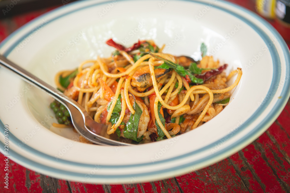 Top view of spaghetti with seafood and thai herb on wooden table
