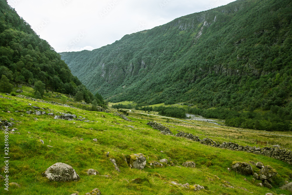 A beautiful green mountain valley near Rosendal in Norway. Autumn landscape in Folgefonna national park. Overcast day. A beautiful green mountain valley near Rosendal in Norway. Autumn landscape in Folgefonna national park. Overcast day.