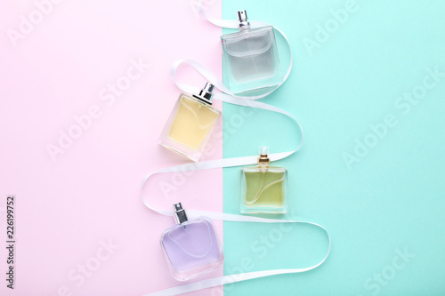 Perfume bottles with ribbon on colorful background