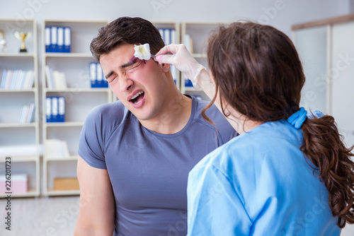 Young man visiting female traumatologist with black eye 