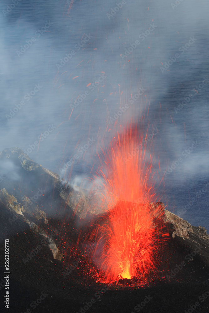 Esplosione Stromboliana di lava incandescente al cratere del Vulcano Stromboli in eruzione con sfondo mare