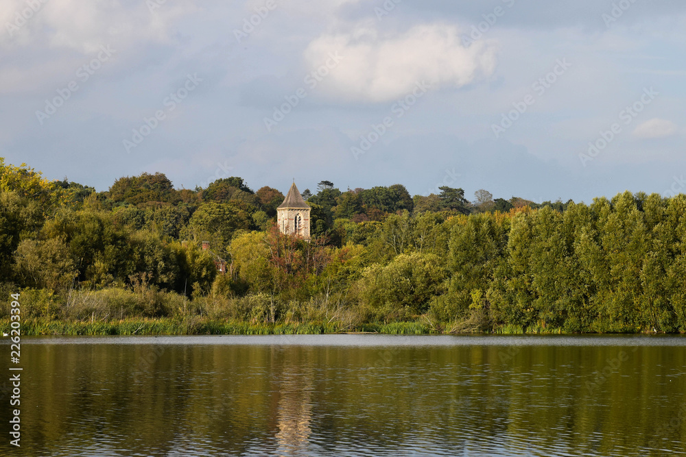 Landscape view over Whittlingham Lake in Norfolk, with old church rising out of the woods.