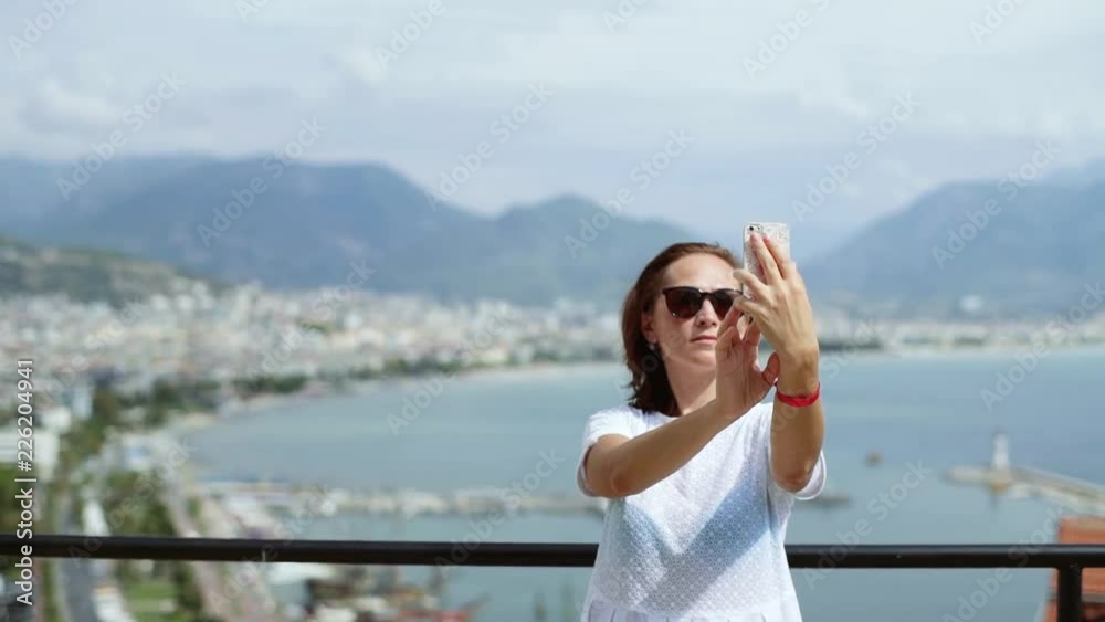 Woman in sunglasses makes selfie on the background of the city. Travel to different cities. Woman in sunglasses makes selfie on the background of the city. Travel to different cities.