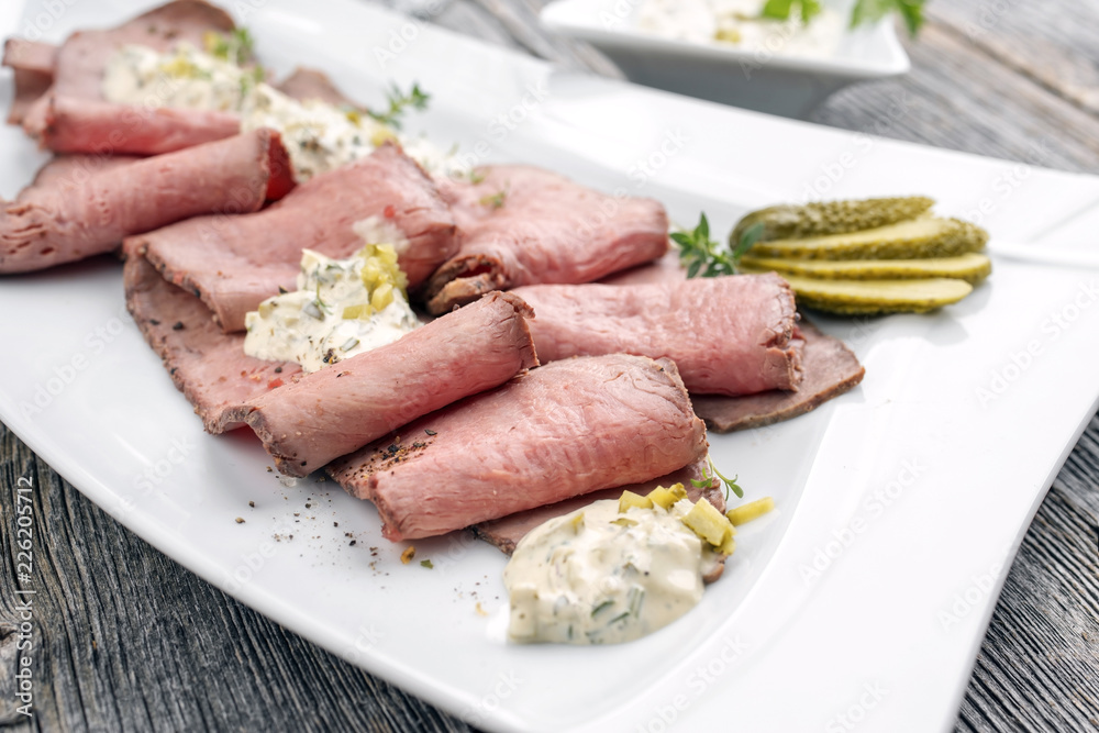 Traditional lunch meat with sliced cold cuts roast beef and remoulade as closeup on a white plate Traditional lunch meat with sliced cold cuts roast beef and remoulade as closeup on a white plate