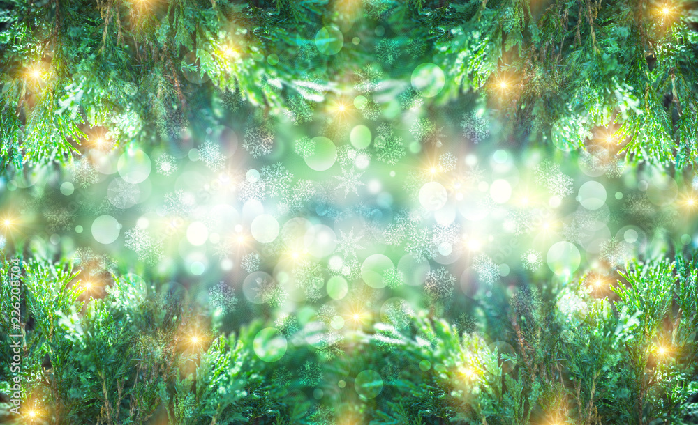 Fototapeta premium Christmas background with fir branches, glow, snowflakes and bokeh.