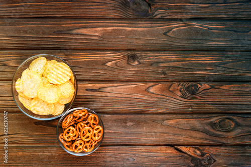 chips, snacks in glass plates on the background of a wooden table. beer snacks. food in front of the TV. fans.