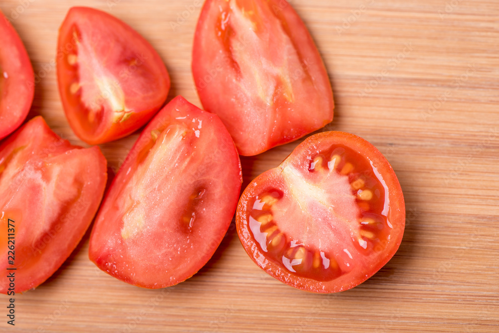 Juicy red tomato chopped on a wooden board on a white background Juicy red tomato chopped on a wooden board on a white background