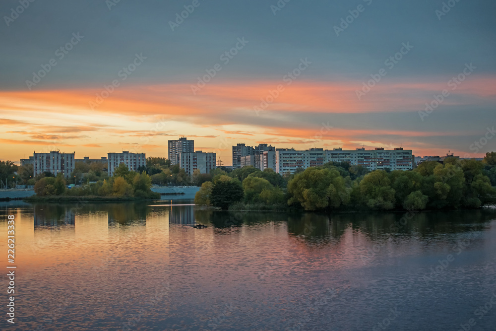 Beautiful cloudy sky at sunset over the river in evening city