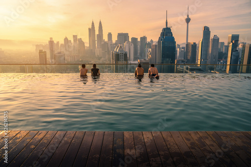 Canvas Print Traveler looking view skyline Kuala Lumpur city in swimming pool on the roof top of hotel at sunrise in Kuala Lumpur, Malaysia