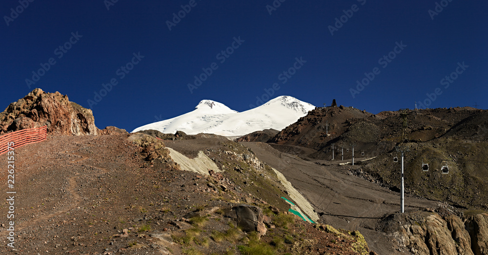 Panoramic view of the southern slope of Mount Elbrus of the Caucasus Mountains in Russia. Snow-covered mountain peaks with two peaks.