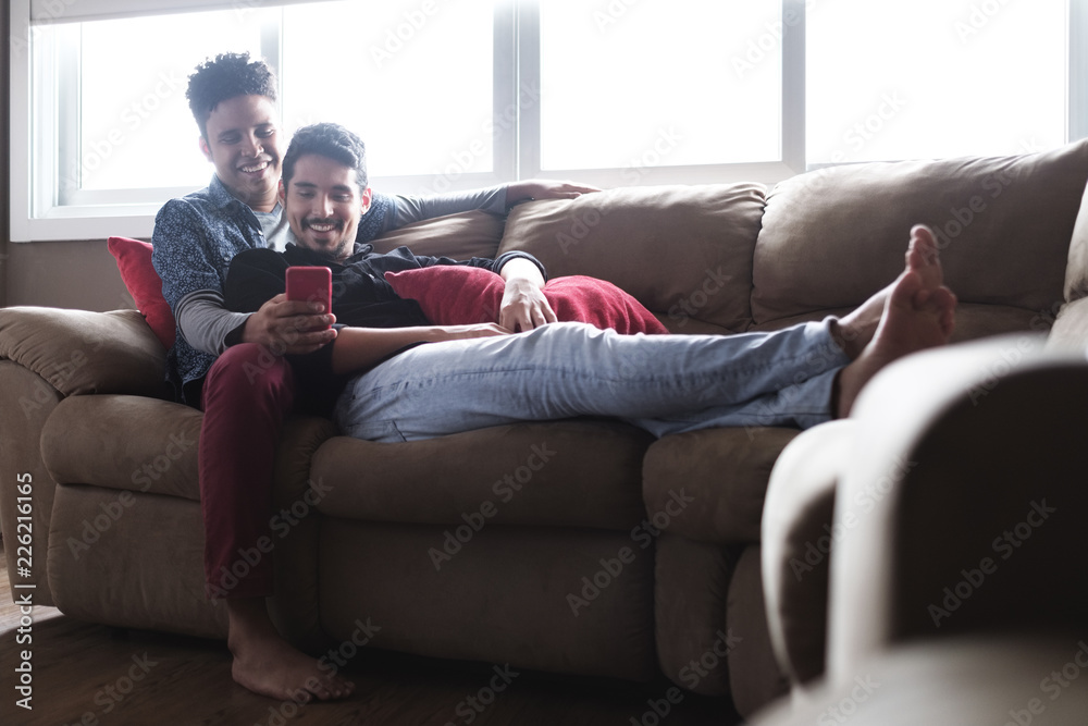 Happy Gay Couple Looking At Pictures On Mobile Phone Happy Gay Couple Looking At Pictures On Mobile Phone