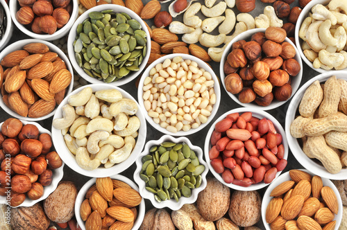 Colorful mix of nut and seed varieties: peanut, cashew, hazelnut, almond, pine nuts, walnut, pumpkin seeds; healthy diet snack; vegan food background