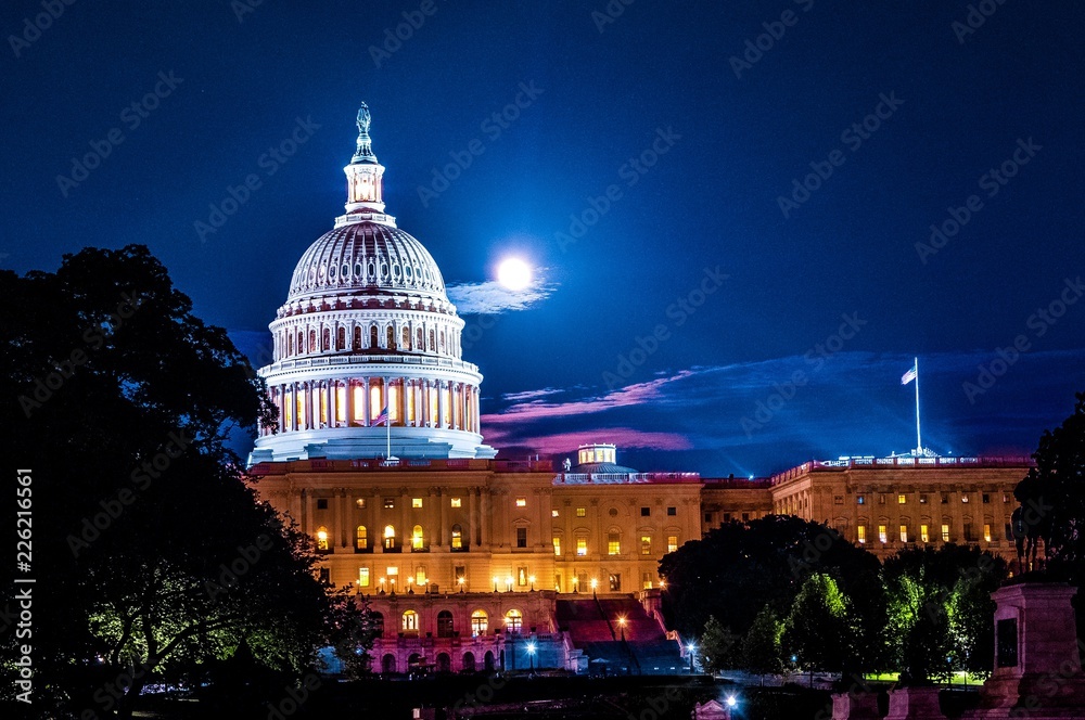 United Stated Capital dome illuminated at night with full moon in background