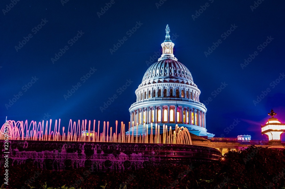 Obraz premium Dome of the marble United States capital building in Washington DC illuminated at night wiht glowing fountain in the foreground