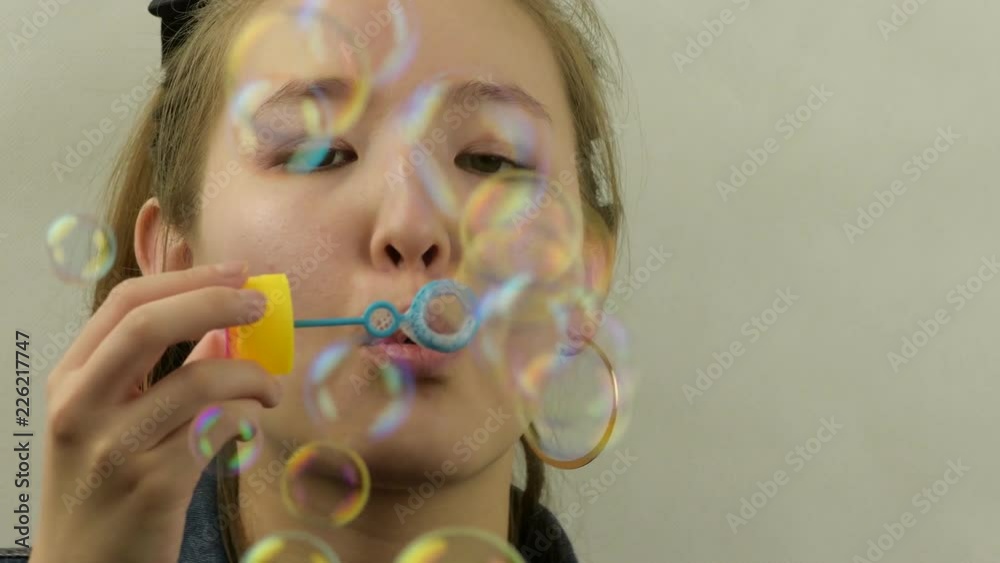 Asian young girl playing with a bubble blower.