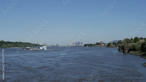 Ferry crosses freighter on Elbe River at sunny day in Hamburg, Germany. Coming from jetty Rueschpark to jetty Teufelsbrueck. photo