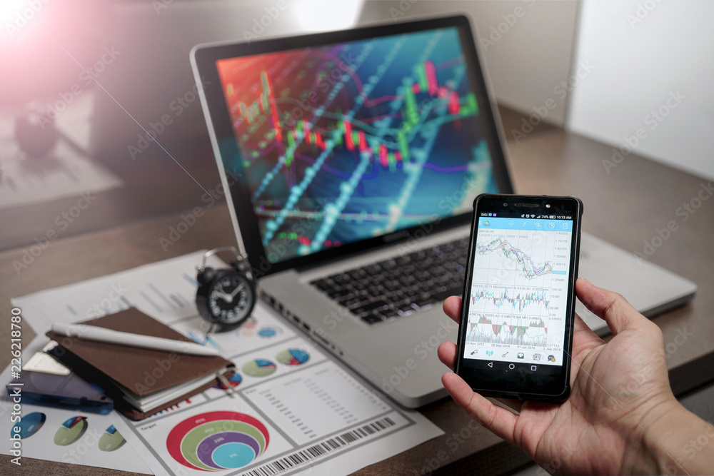 A Computer Tablet and ultra-slim smartphone with candle stick chart on the screen a business and finance conceptual A Computer Tablet and ultra-slim smartphone with candle stick chart on the screen a business and finance conceptual