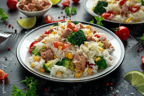 Fresh Tuna rice salad with sweet corn, cherry tomatoes, broccoli, parsley and lime in black bowl