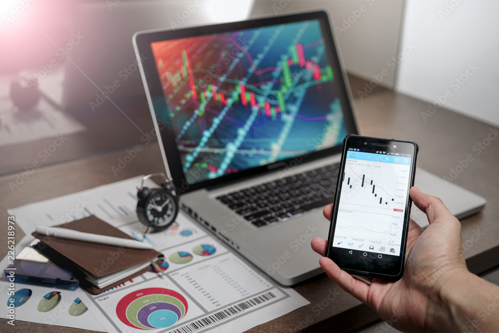 A Computer Tablet and ultra-slim smartphone with candle stick chart on the screen a business and finance conceptual A Computer Tablet and ultra-slim smartphone with candle stick chart on the screen a business and finance conceptual