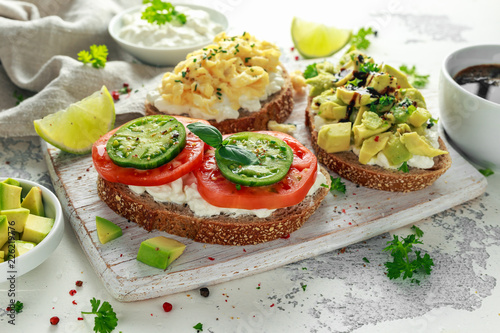 Vegetarian Healthy bread toasts with cottage cheese, heirloom tomatoes, scrambled eggs and avocado