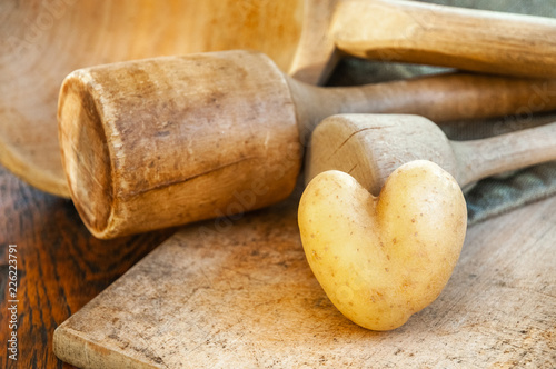 Eine Herzkartoffel mit Küchenutensilien in Massivholz in einer Landhausküche steht für die Liebe zum gesunden Kochen