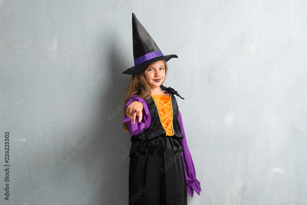Little girl dressed as a witch for halloween holidays pointing to the front Little girl dressed as a witch for halloween holidays pointing to the front