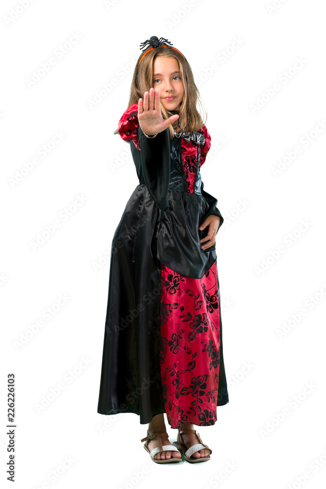A full-length shot of a Blonde child dressed as a vampire for halloween holidays making stop gesture with her hand isolated on white