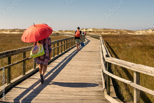 Fototapeta Naklejka Na Ścianę i Meble -  Beach goers walk on wooden path toward the beach of Carnota in Galicia, Spain.