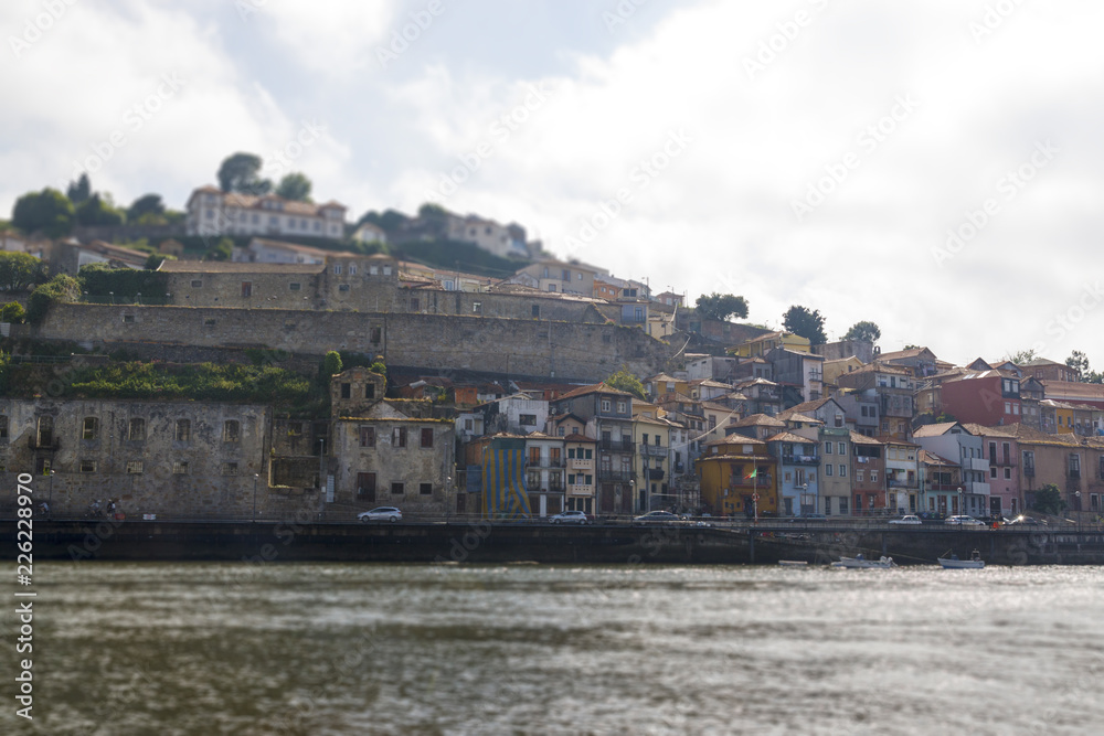 Fototapeta premium Tilt-shift effect photography. View of the Ribera from the water, Porto, Portugal. Colorful houses on the embankment of the river Douro.