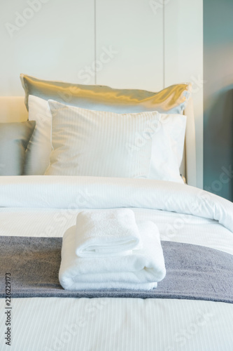 Clean white towels setting on bed in bedroom