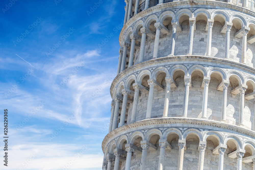 Closeup on the structure of the famous Leaning Tower of Pisa, Italy with blue cloudy sky in the background.