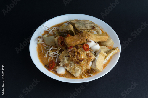 Curry noodles in a plate on dark background with selective focus and crop fragment