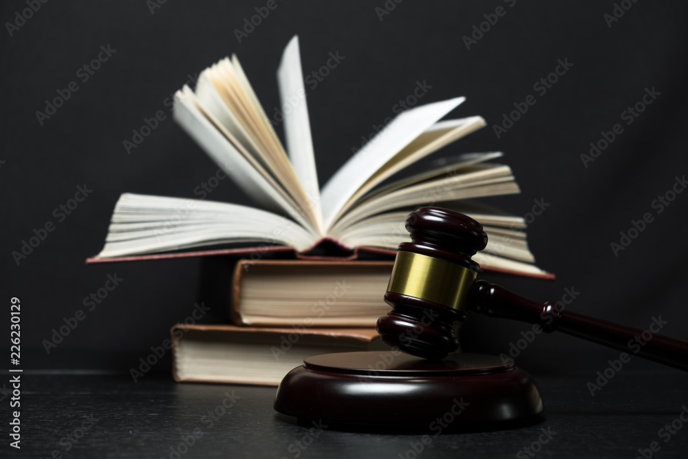 Judge gavel beside pile of books on black wooden background Judge gavel beside pile of books on black wooden background