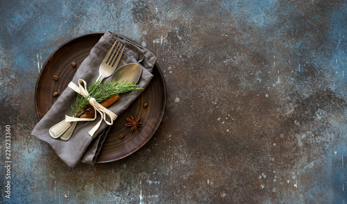Chrismas table place setting. Tableware with evergreen twigs, cone and spice