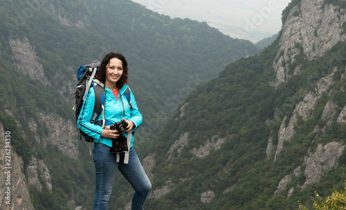 A woman tourist is going to shoot on a mountain landscape.