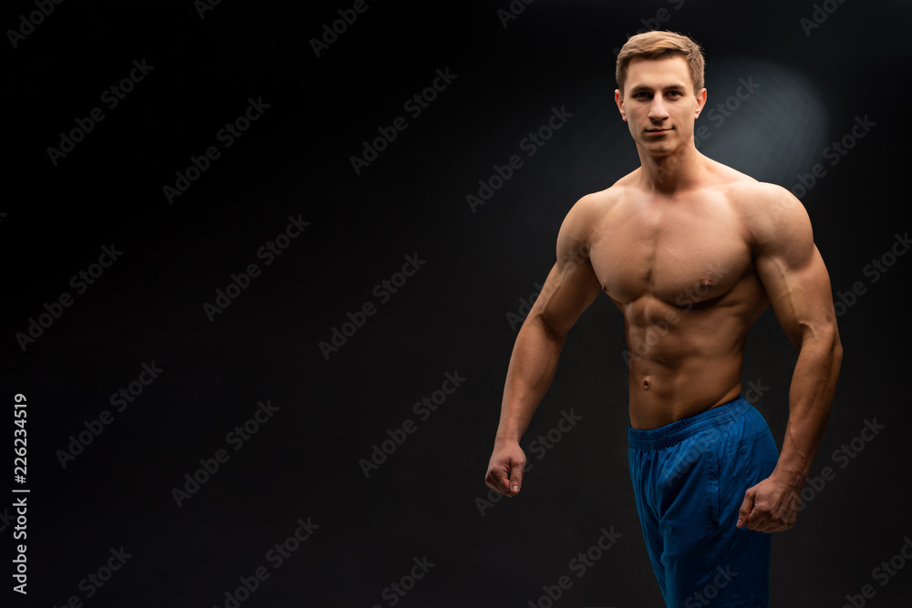 Sports wallpaper on dark background. Power athletic guy bodybuilder. Sport nutrition banner.