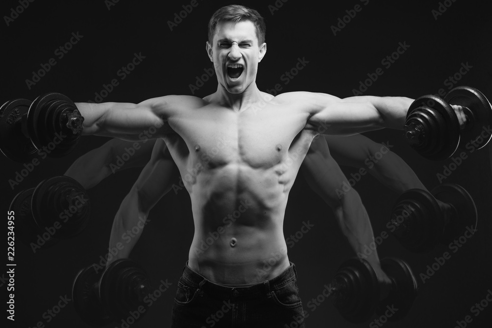 Black and white conept image Dumbbell Lateral Raise Bodybuilder turning back raising hands pumping up shoulders muscle exercise Power Partials routine with dumbbells on gym Dramatic studio shot