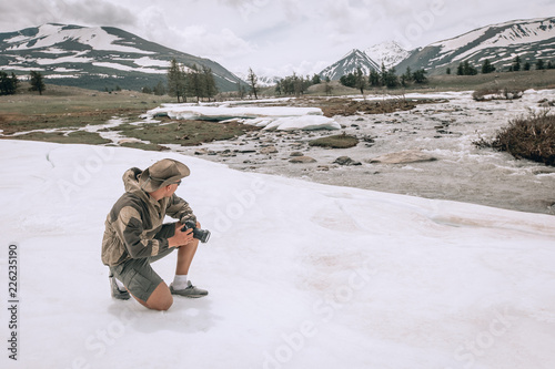young man taking pictures in winter snow field park Tourist. in Mongolia snow landscape, spring