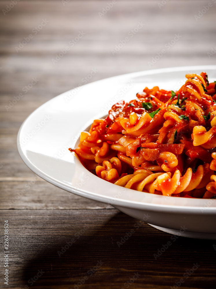 Pasta with tomato sauce and vegtables on wooden table Pasta with tomato sauce and vegtables on wooden table
