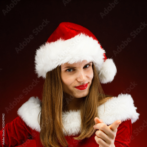 Beautiful woman in Santa Claus clothes pointing