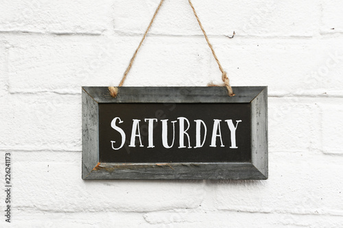 Hello saturday finally weekend text on hanging board white brick outdoor wall photo