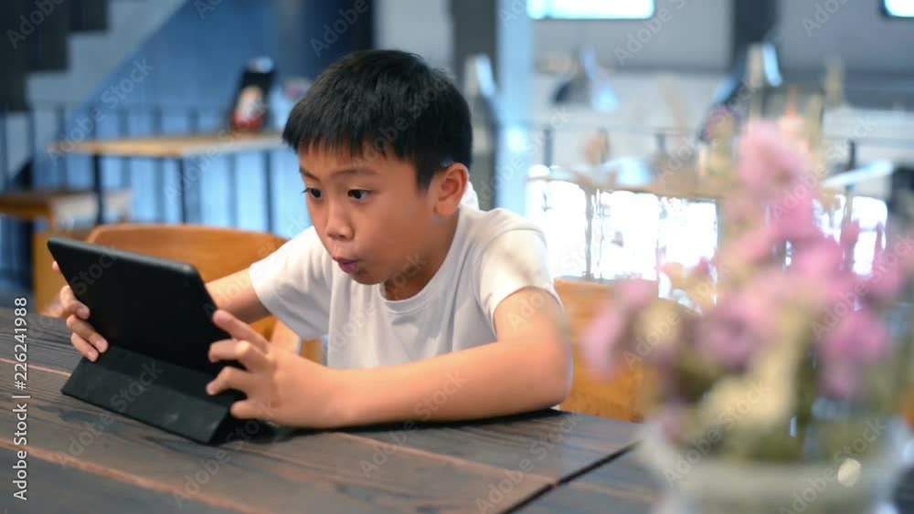 Asian boy playing online game with tablet computer Asian boy playing online game with tablet computer