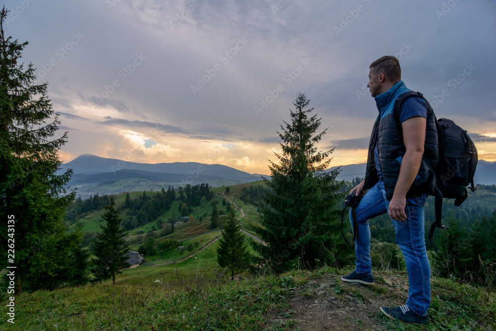 A tourist in the middle of the mountains looks at the sunset. Nature, travel, tourism 